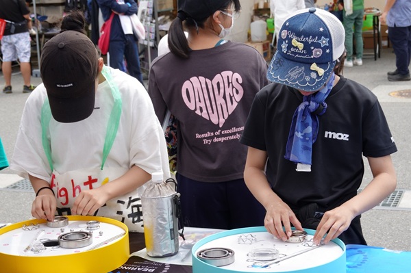 NTN　TOJ2026　NTN、ツアー・オブ・ジャパン 2026に協賛、全8ステージで「NTN 回る学校」を開催 NTNの販売子会社であるNTNセールスジャパンは、5月24日～31 日にかけて全国８ステージ（堺、京都、いなべ、大鹿、信州飯田、富士山、相模原、東京） で開催される国内最大規模の国際自転車ロードレース「ツアー・オブ・ジャパン 2026」（TOJ、https://www.toj.co.jp/2026/）に協賛し、親子でベアリング（軸受） について学ぶことができる「NTN 回る学校」を各レース会場で開催する。  TOJ は、UCI（国際自転車競技連合）公認の国内最高峰の国際自転車ロードレースで、今年で28 回目の開催を迎えます。本大会には国内外より世界トップクラスの選手が所属する16 チームが参加し、8 日間にわたりハイレベルなレースを展開する。NTNは昨年に 引き続き本大会に協賛する。  今回の「NTN 回る学校」では、ベアリングの組み立て体験に加えて、ベアリングのシール構造や潤滑油の違いによって変わる回転トルクの差を、実際に触れながら体感できる展示を実施する。子どもから大人まで、楽しみながらベアリングや省エネルギーに関する理解を深めることのできるコンテンツが用意されている。  NTNは、ロードバイクに使用される高級ハブにベアリングが採用されるなどの実績を有しており、自転車の安全でなめらかな走行に貢献している。同社では今後も、環境に優しい移動手段である自転車市場の発展に貢献するとともに、環境負荷の低減にも取り組んでいく。  ベアリングの組み立て体験のようす：外輪、内輪、保持器、ボールを組み合わせてベアリングの組み立てに挑戦できる。初めてベアリングを見る人も、ベアリングの構造や仕組みについて学べる　bmt　ベアリング＆モーション・テック
