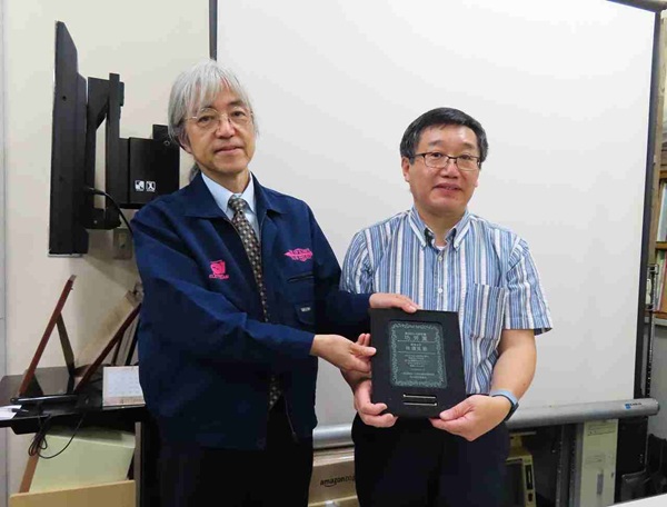 第105回ELID研削セミナー　贈呈式のようす：大森委員長（左）と功労賞受賞の林氏（右）　bmt　ベアリング＆モーション・テック